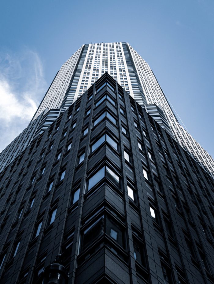A low angle shot of a tall city building with a blue sky in the background  in New York